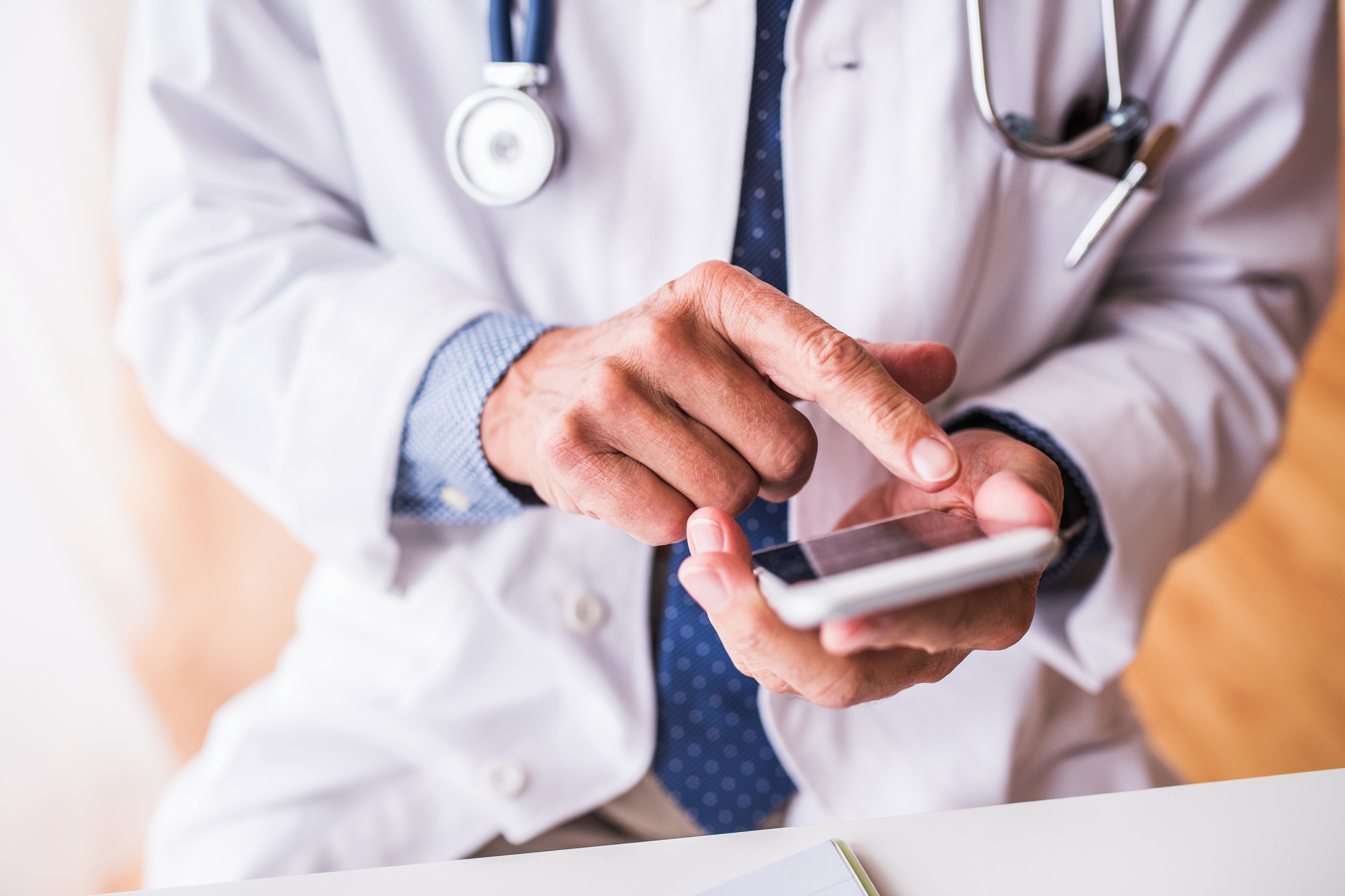 Senior doctor with smartphone working at the office.